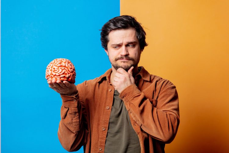 Guy in shirt hold human brain on yellow and blue backgrounds
