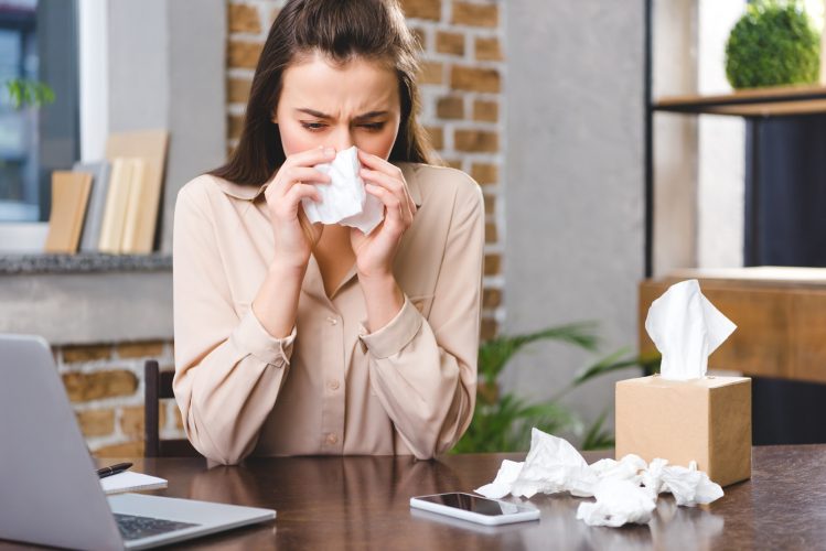 young businesswoman suffering from allergy at workplace
