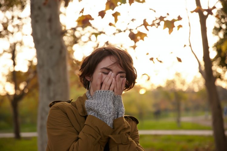 Joyful young pretty short haired brunette woman covering her face with raised palms while laughing