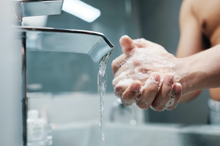 Man Washing Hands With Water And Soap In Bathroom