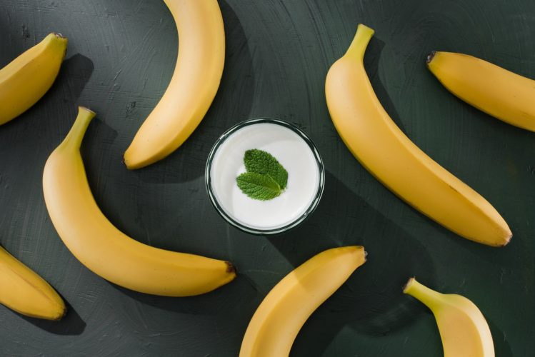 top view of bananas and milkshake glass with mint on table