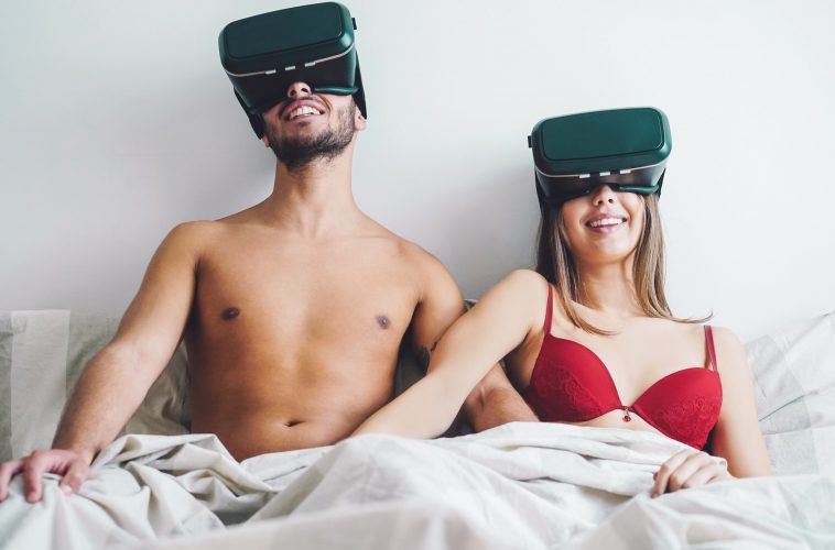 Young couple masturbating while using virtual reality glasses in the bed