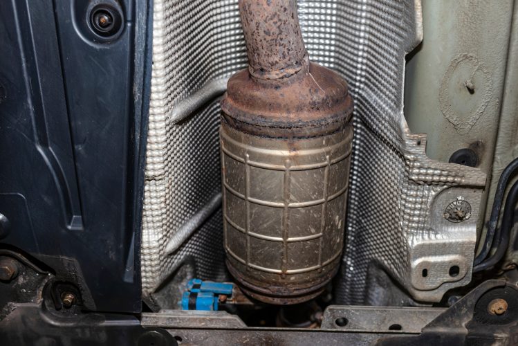 A diesel particulate filter in the exhaust system in a car on a lift in a car workshop, seen from be