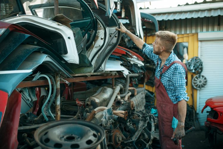 Male mechanic choosing door on car junkyard