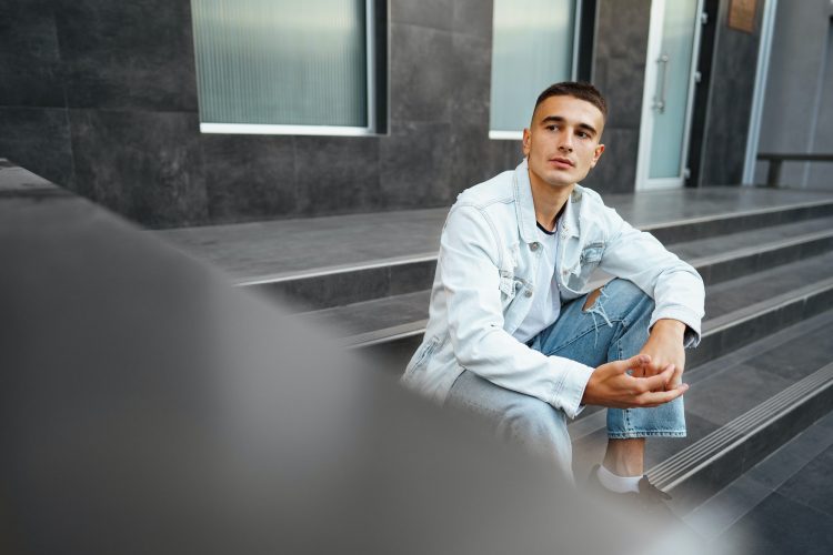 Young casual man sitting on stairs alone on street