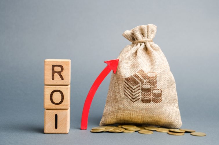 Wooden blocks with the word ROI and the up arrow with the money bag