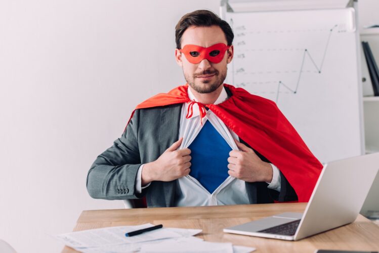 handsome super businessman in mask and cape showing blue shirt in office