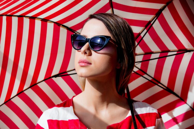 woman in sunglasses with red striped umbrella