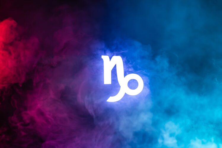 blue illuminated Capricorn zodiac sign with colorful smoke on background