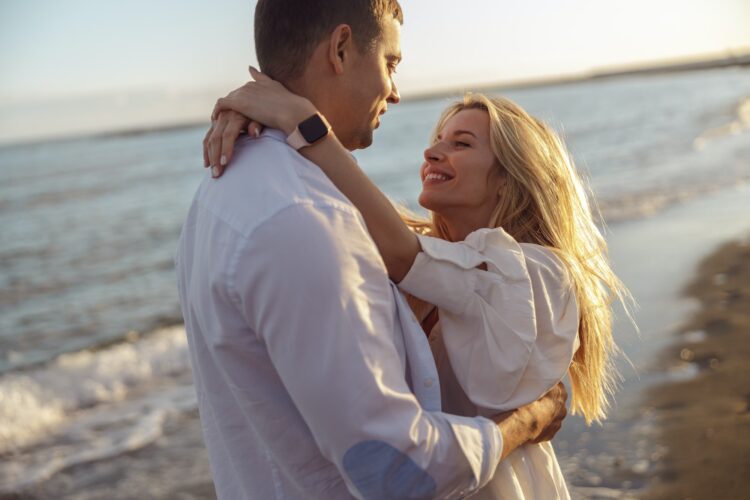 Portrait of happy couple hugging while standing on beach