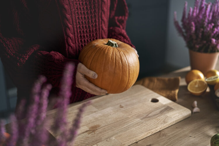 Close up of woman holding big pumpkin in the kitchen