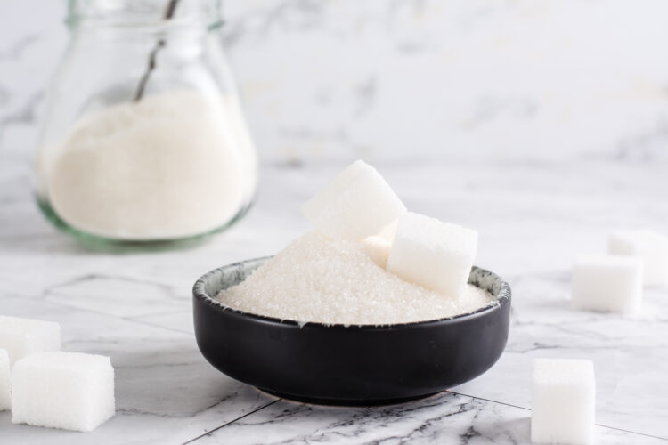 Granulated sugar and sugar cubes in a bowl and sugar in a jar on the table.