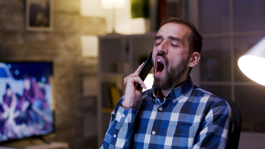 Overworked businessman yawn during a conversation on mobile phone