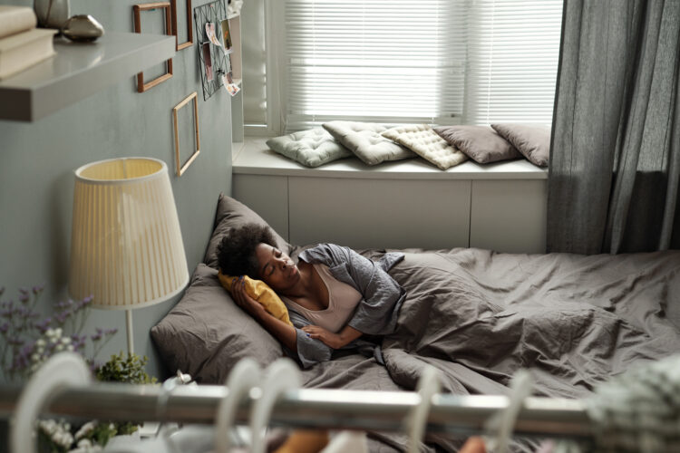 Contemporary young woman lying in bed in home environment