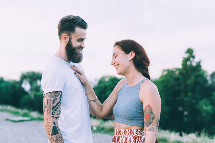 Couple of young woman and man bearded lover talking and laughing outdoor in sunset