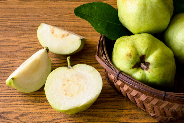 Fresh guava fruit in basket on wooden table background.
