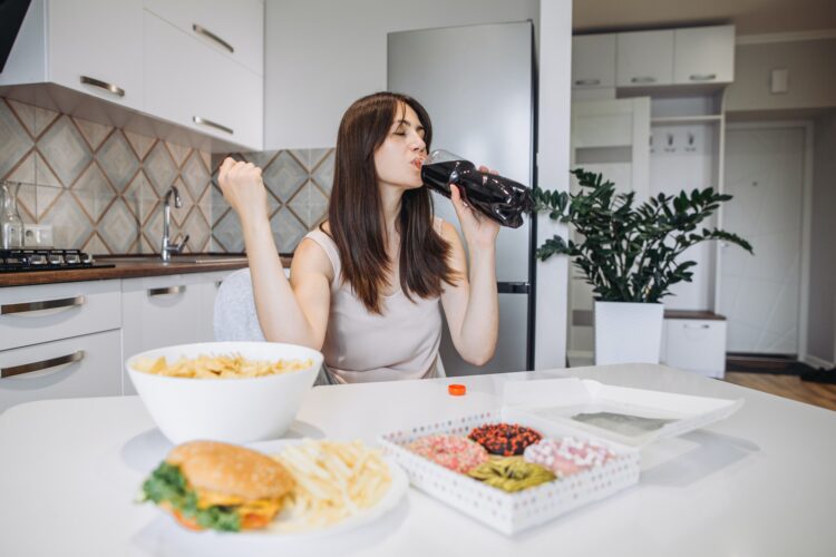 A woman eats junk food at home in the kitchen.